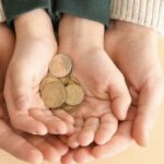 mani di un madre e mani di un figlio che mantengono delle monete