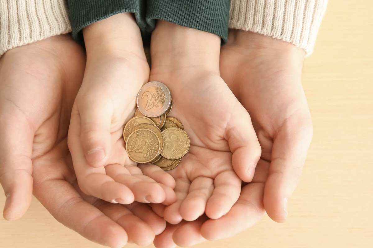 mani di un madre e mani di un figlio che mantengono delle monete 